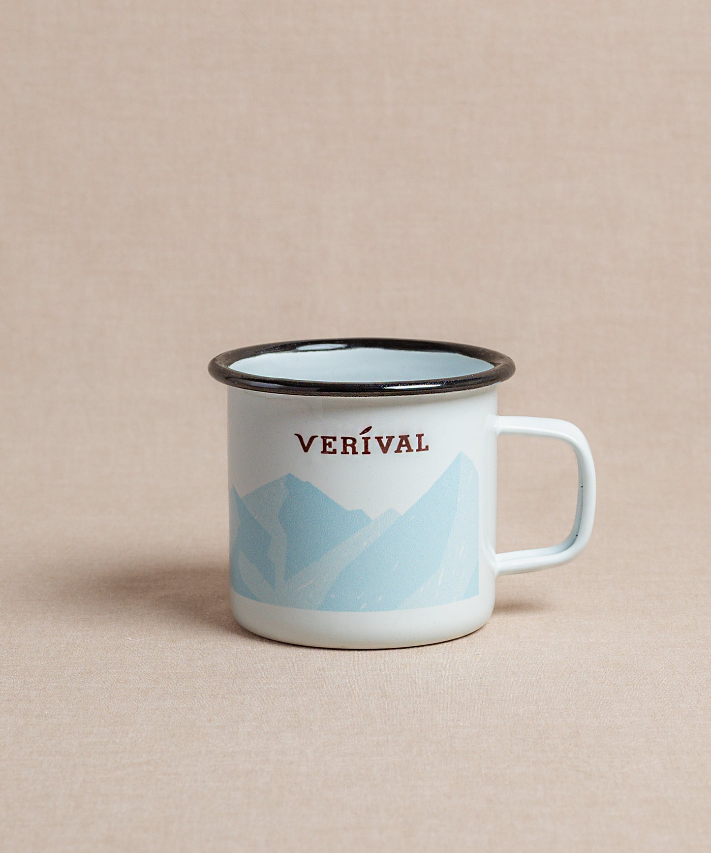 Die Verival Emaille-Tasse mit schwarzem Rand, dem roten Schriftzug „Verival“ und einem hellblauen Bergmotiv auf weissem Untergrund ist perfekt für den morgendlichen Kaffee- oder Teegenuss. Marke: Verival Bio.
