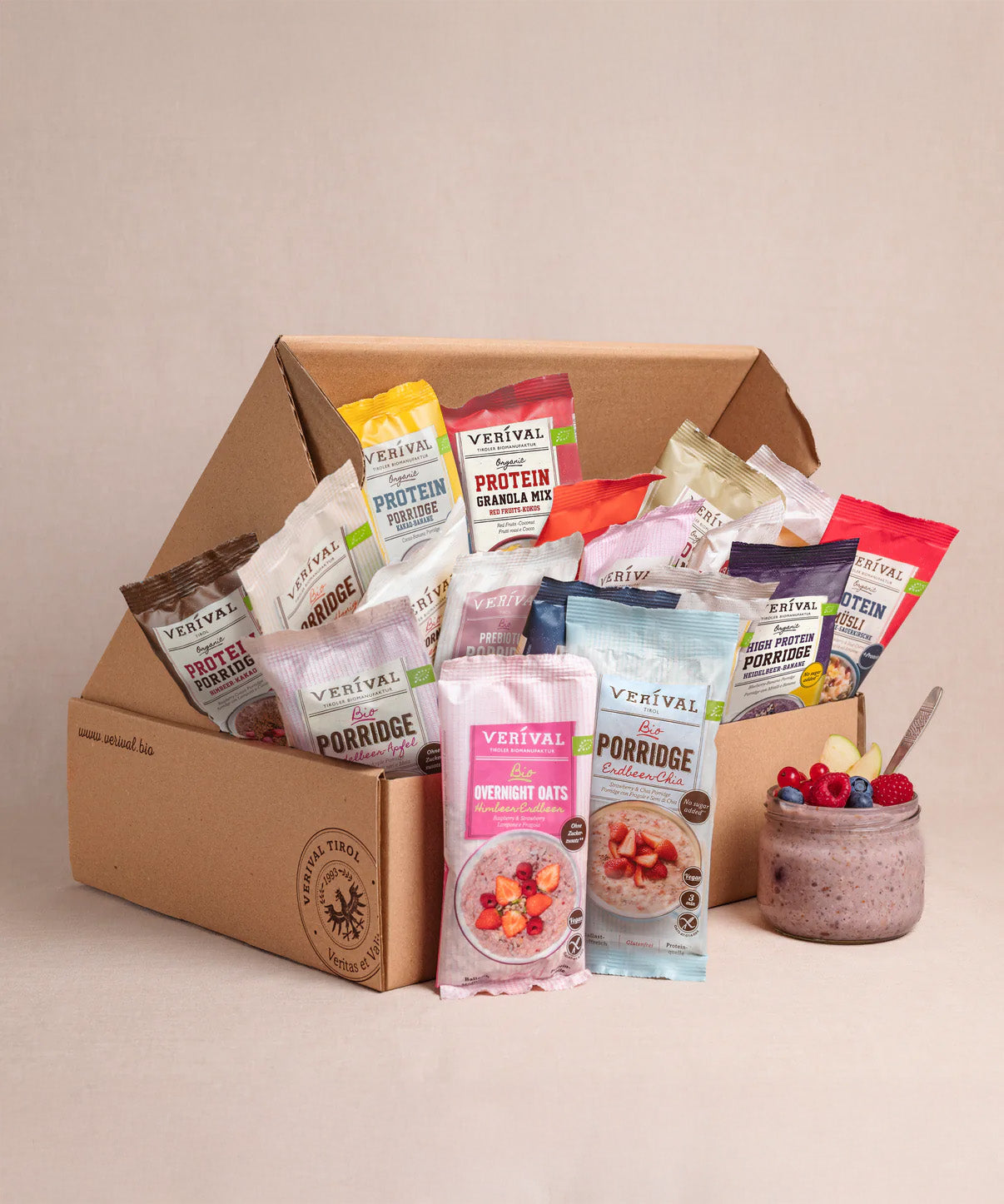Die Verival Bio GmbH 30 Tage Gesund frühstücken Box mit verschiedenen Frühstücks-Sachets steht neben einer Schüssel mit Beeren und Overnight Oats - perfekt für gesunde Frühstücksideen mit veganen Bio Zutaten.